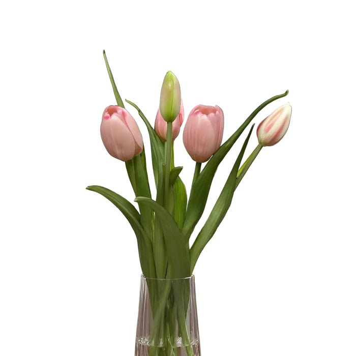 Clear vase with pink tulips on a marble surface in a living room setting