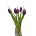 Clear vase with purple tulips on a wooden table