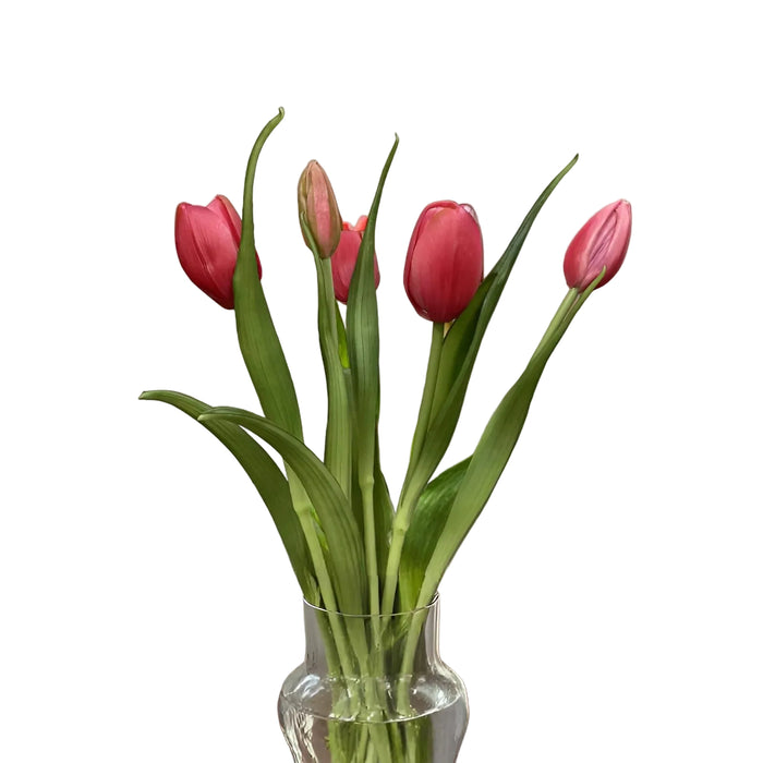Clear glass vase with pink tulips on a wooden table