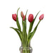 Clear glass vase with pink tulips on a wooden table
