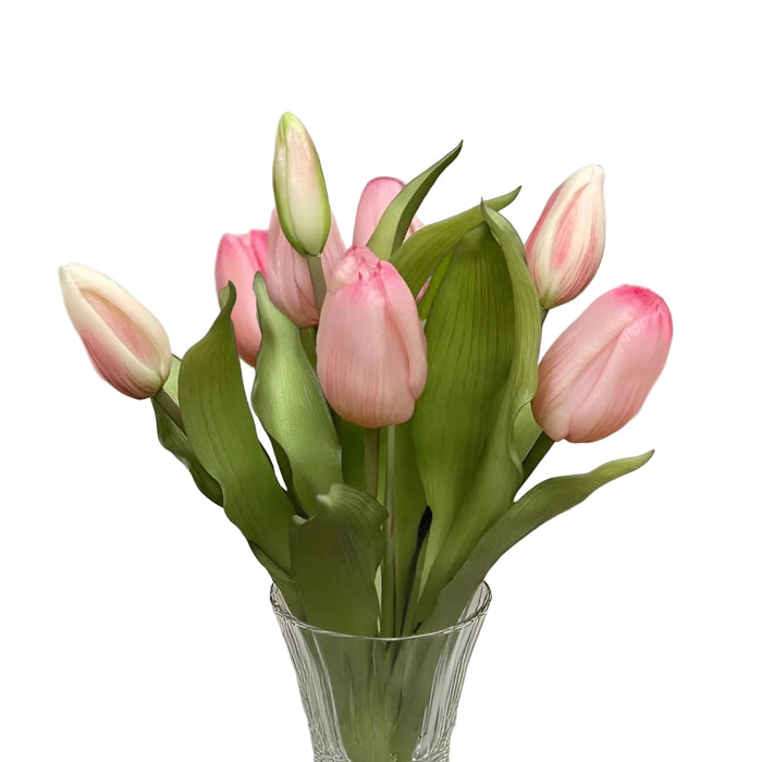 Clear glass vase with pink tulips on a white surface and light gray background