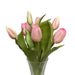 Clear glass vase with pink tulips on a white surface and light gray background