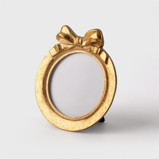 Gold picture frame with a bow design on a white background