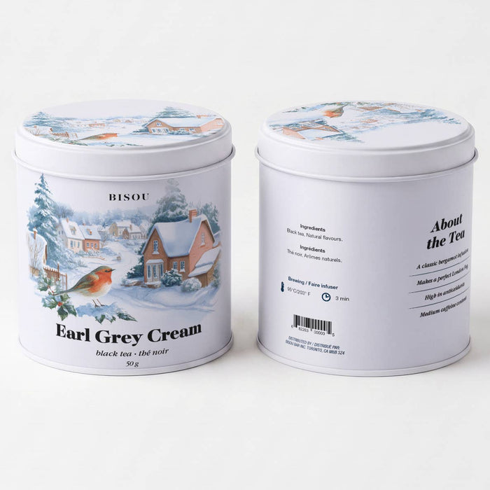 Two white metal tea tins shown on a clean white background, one displaying the front label with a winter village illustration and the word 'BISOU', and the other showing the side/back with product details and text for 'Earl Grey Cream'.