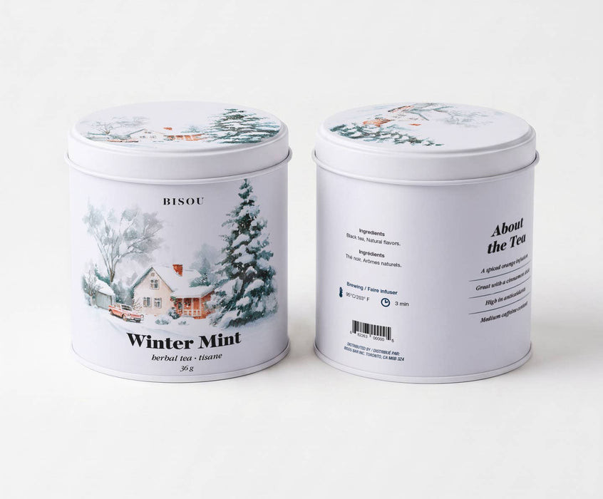 Two white cylindrical metal tea tins with winter-themed illustrations, showing the front and back labels of BISOU Winter Mint herbal tea.