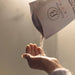 Hand receiving a small amount of product from a 'Bathorium' package.