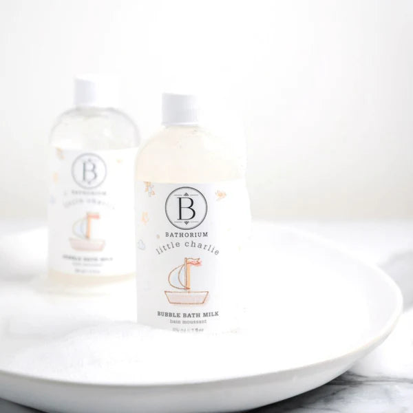 Two bottles of Bathorium bubble bath milk on a white plate with a white background