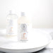 Two bottles of Bathorium bubble bath milk on a white plate with a white background