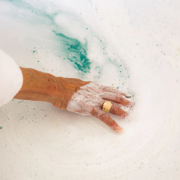Hand with a ring in a bathtub filled with bubbles