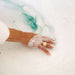 Hand with a ring in a bathtub filled with bubbles