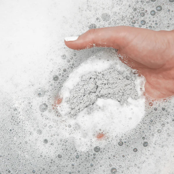 Hand interacting with soapy water on a white background