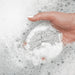 Hand interacting with soapy water on a white background
