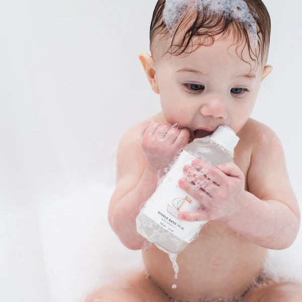 Baby holding a bottle of baby wash with a white background