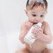 Baby holding a bottle of baby wash with a white background