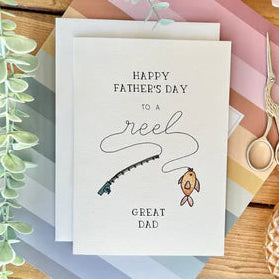 Father's Day card with fishing theme on a decorative table with scissors and flowers.